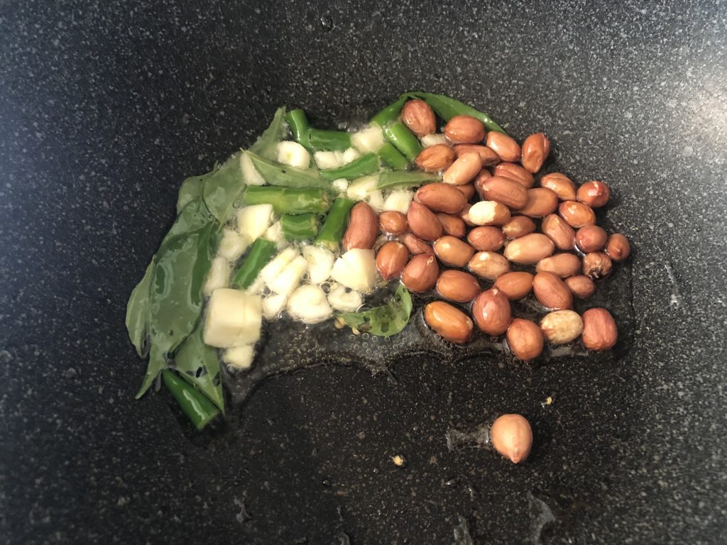Add curry leaves chilly garlic peanuts in murmura chivda